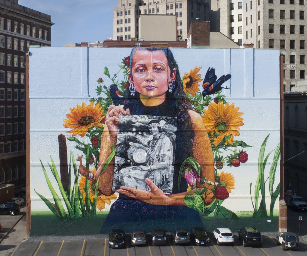 Still Here, in Providence, depicts Narragansett artist Lynsea Montanari holding a portrait of Narragansett/Wampanoag leader Princess Redwing.